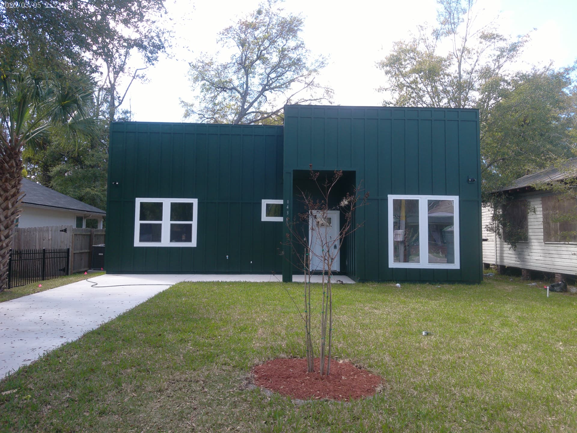 Front elevation of the completed modern home at 1436 Florida Avenue with dark green board-and-batten siding