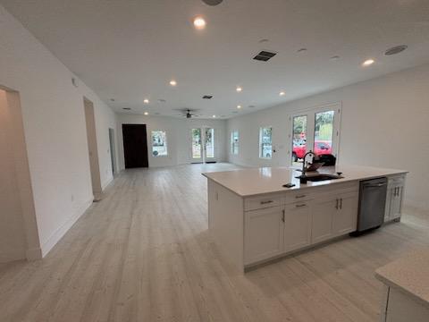 Open kitchen island with quartz countertop, shaker cabinets, and stainless dishwasher