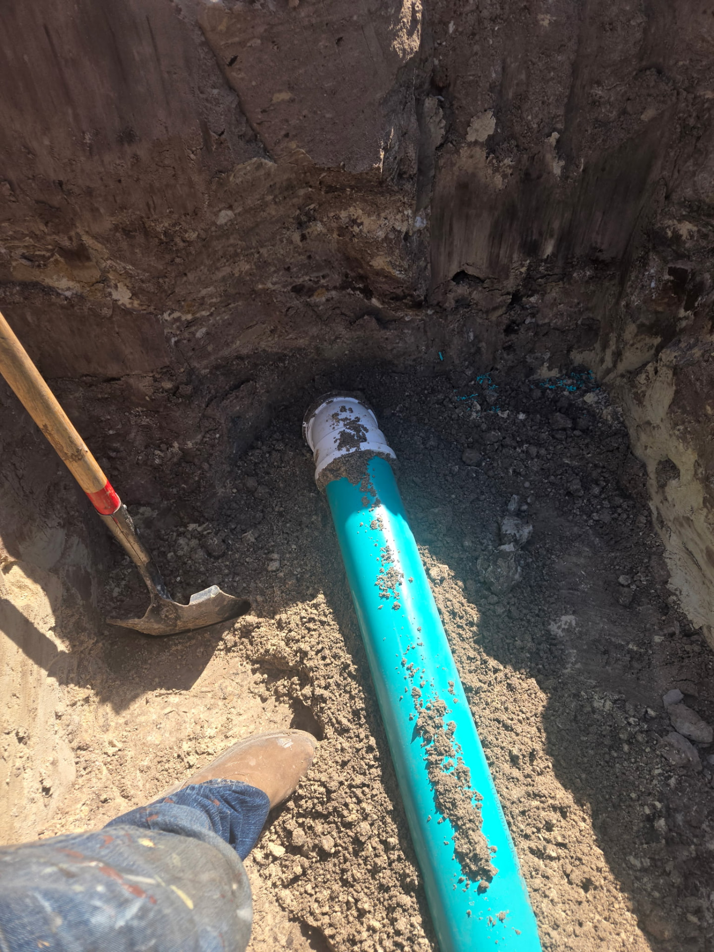 Crew member setting new PVC water main pipe in a shored trench