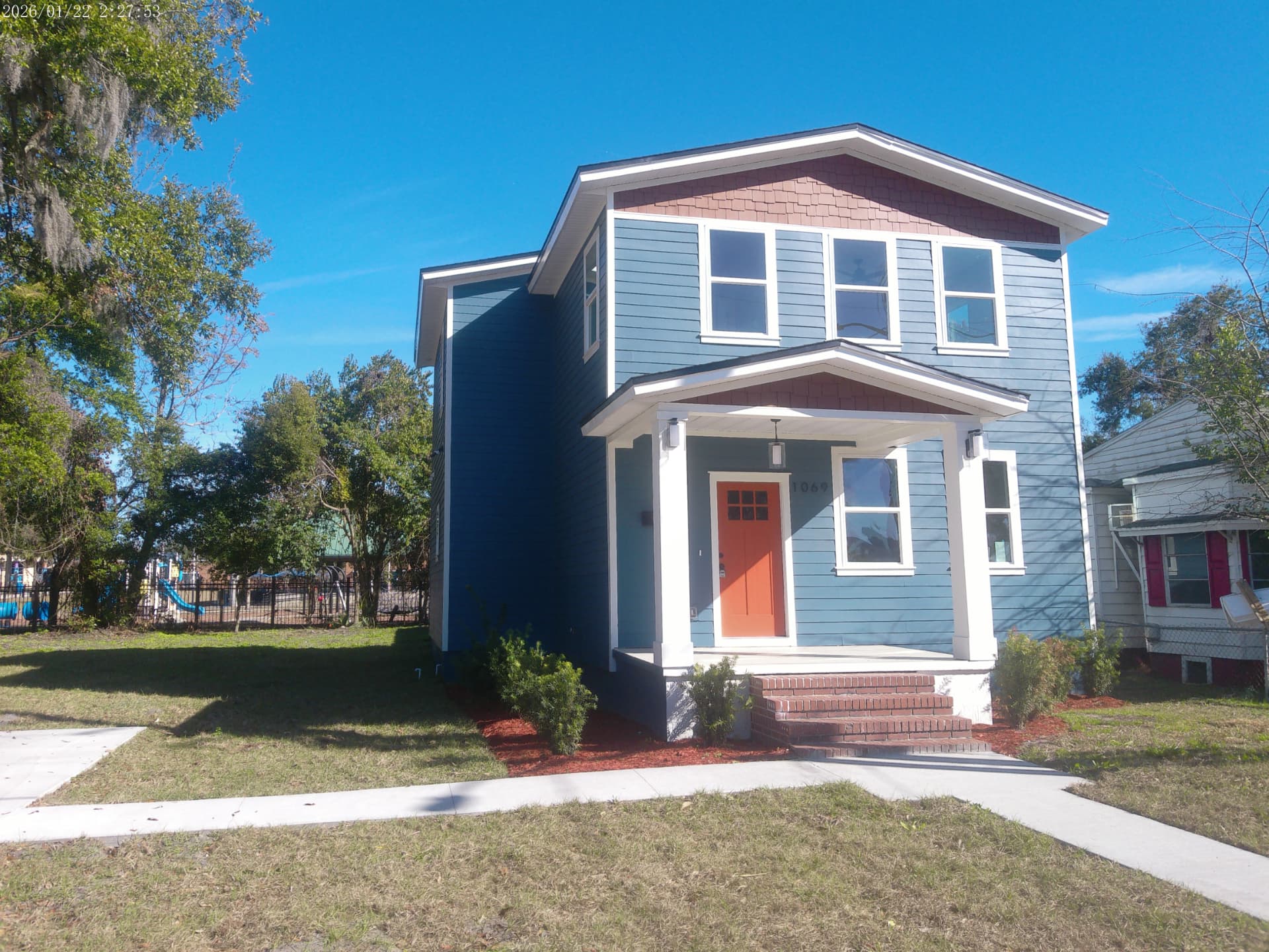 Front elevation of the completed two-story home at 1069 Spearing Street with covered porch and orange front door