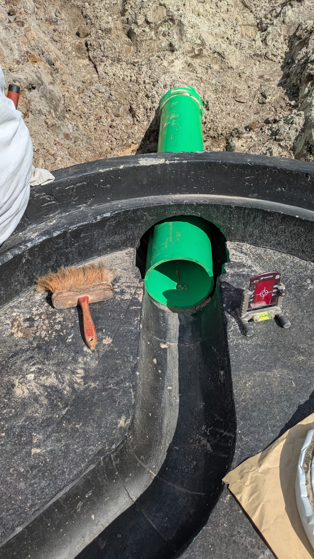 Green sewer pipe entering a Type-A manhole base with an invert channel
