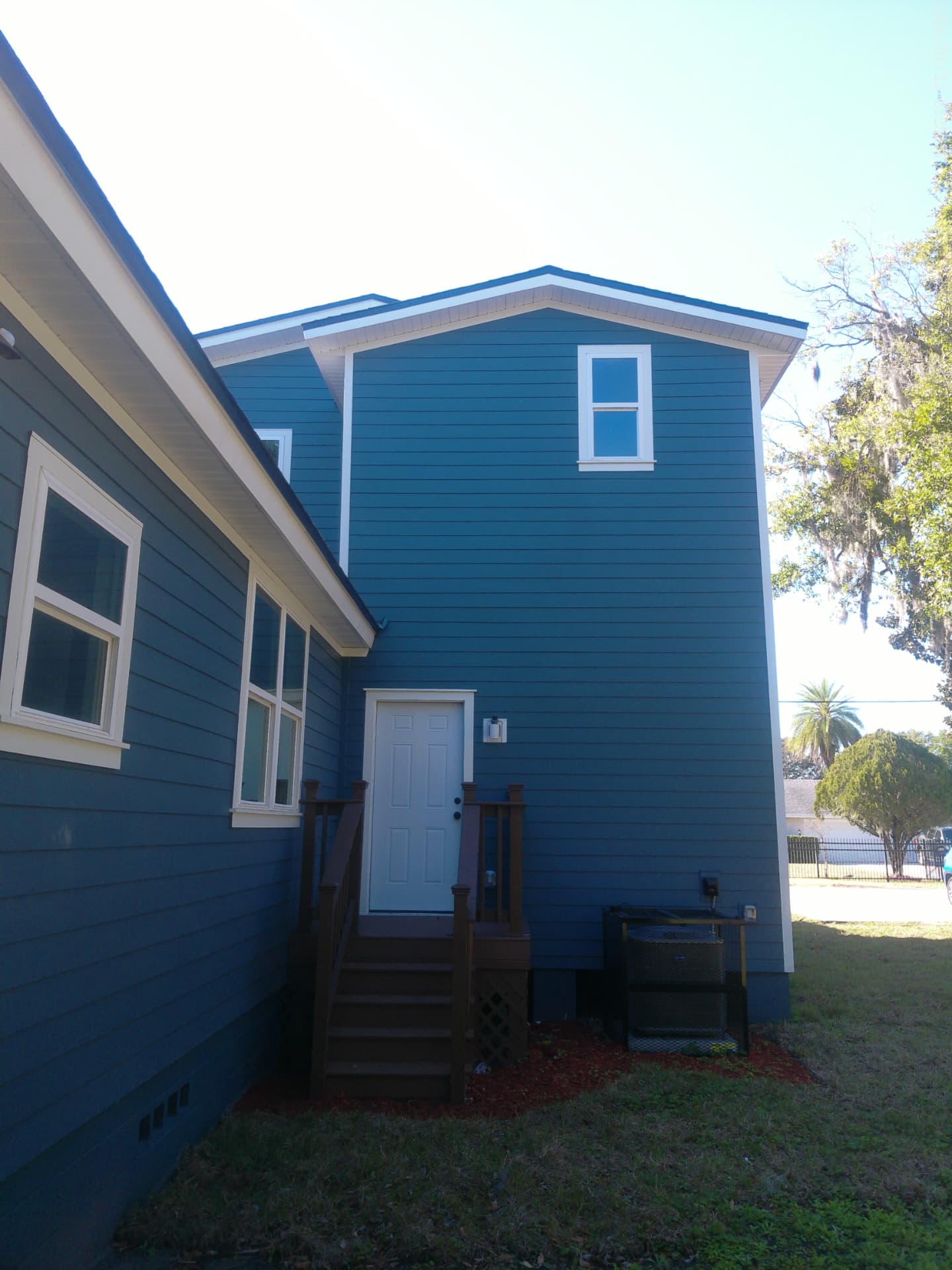Rear of the Spearing Street home with service entry, wood deck, and HVAC condenser