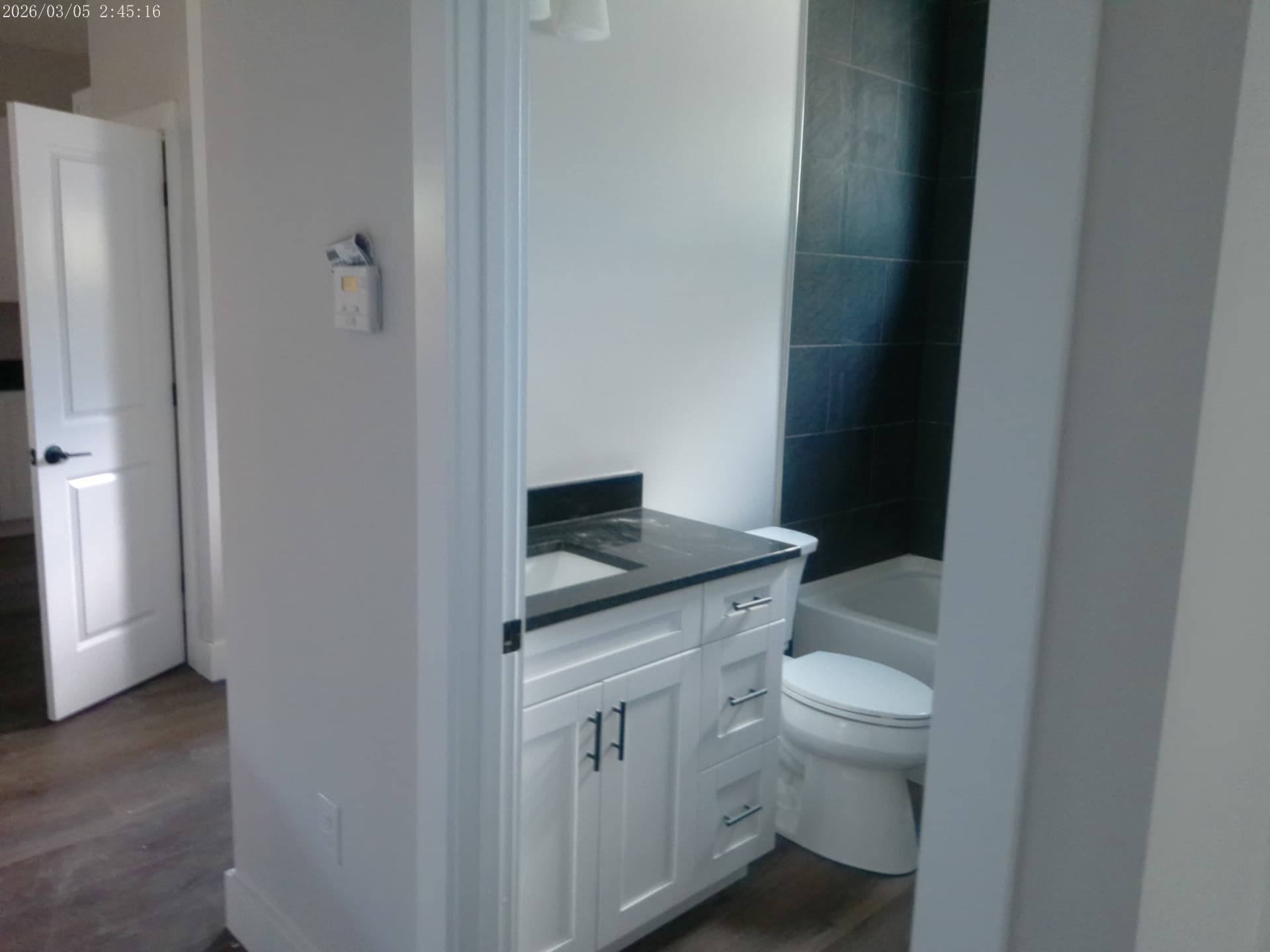 Finished bathroom with tile tub surround, granite vanity, and matte-black fixtures
