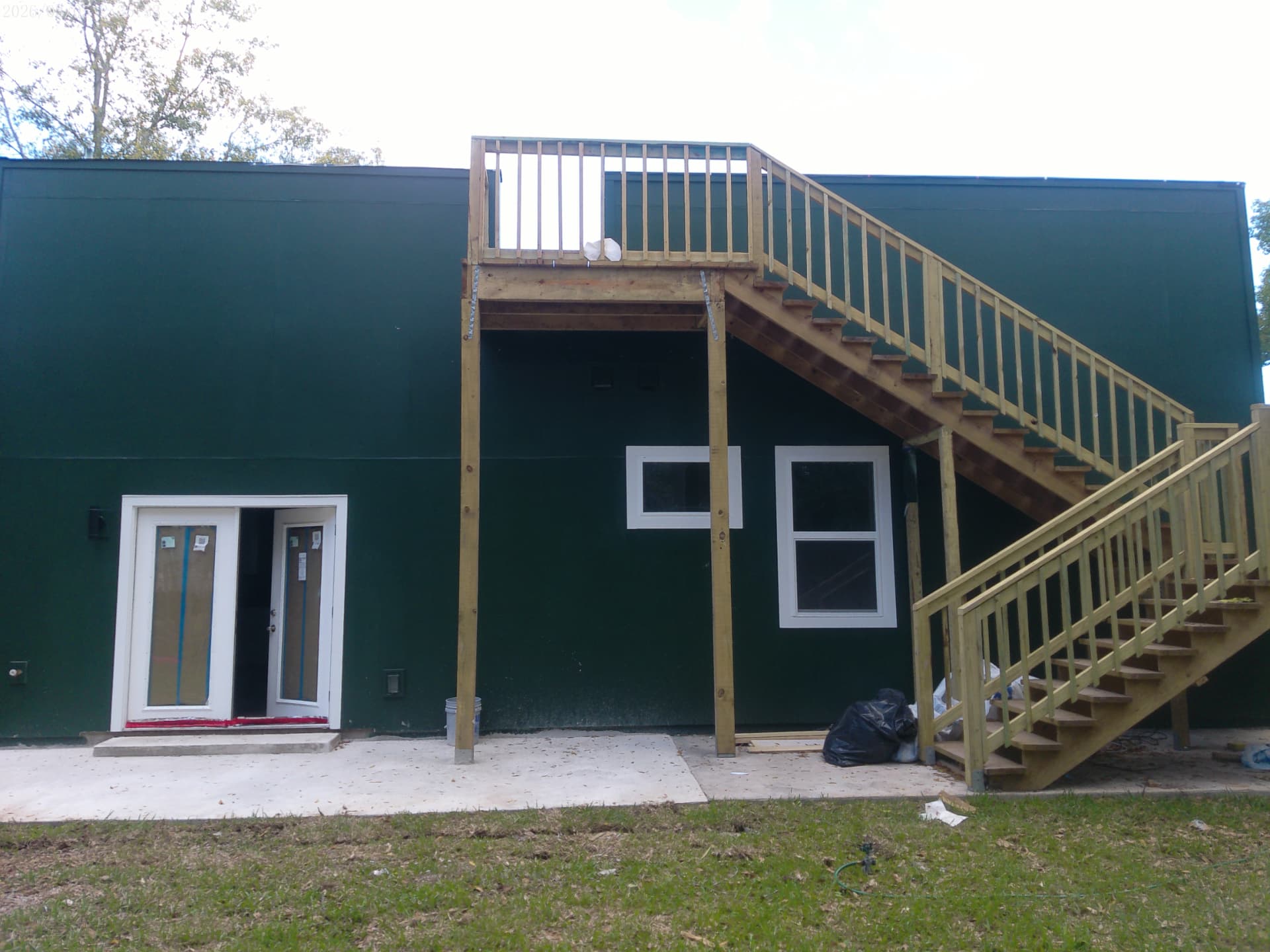 Rear elevation of the home showing elevated deck, exterior stair, and service entry